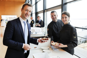 Ein Tagungsteilnehmer im Anzug steht an der Catering-Ausgabe im Seefoyer im Festspielhaus Bregenz mit Blick auf den See