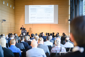 Vollbesetzte Reihenbestuhlung, eine Bühne mit Rednerpult und Leinwand im Seefoyer im Festspielhaus Bregenz