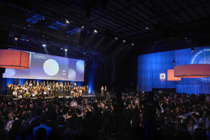 Menschen an Galabetischung und auf der Bühne vor einer großen Leinwand auf der Werkstattbühne im Festspielhaus Bregenz