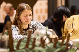 Ein Adventhock-Teilnehmerin arbeitet konzentriert an einem Adventkranz im Seefoyer des Festspielhauses Bregenz