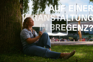 Eine Frau sitzt an einen Baum gelehnt vor dem Festspielhaus Bregenz