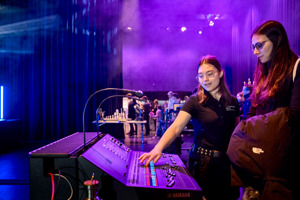 Ein weiblicher Lehrling erklärt einer Besucherin des Tags der offenen Tür ein Mischpult auf der Seitenbühne