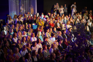 Vollbesetzte Reihenbestuhlung mit bunt gekleideten Frauen in der Werkstattbühne des Festspielhauses Bregenz