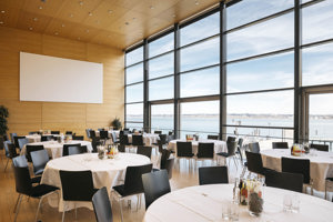 Runde Tische mit weißen Tischdecken und schwarzen Stühlen im Seefoyer im Festspielhaus Bregenz
