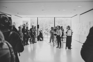Tagungsteilnehmer:innen stehen im Saal Bodensee und hören einer Sprecherin zu, Festspielhaus Bregenz