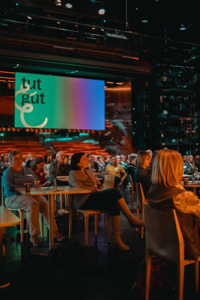 Tagungsteilnehmer:innen sitzen an Tischen auf der Hauptbühne im Festspielhaus Bregenz